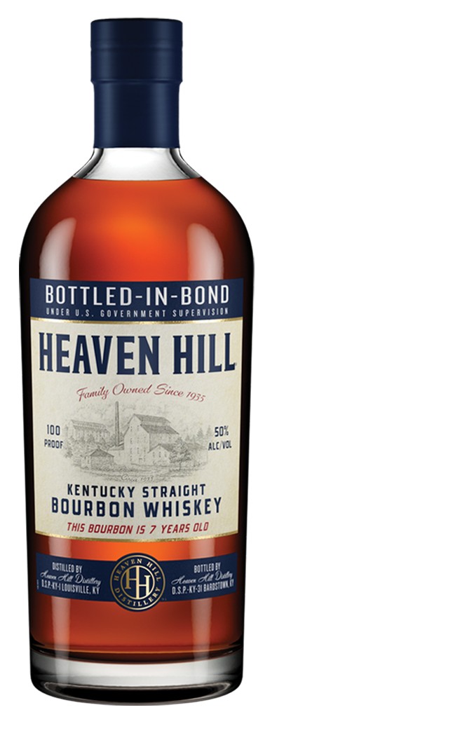 Bourbon in a Glencairn glass against stacked oak barrels